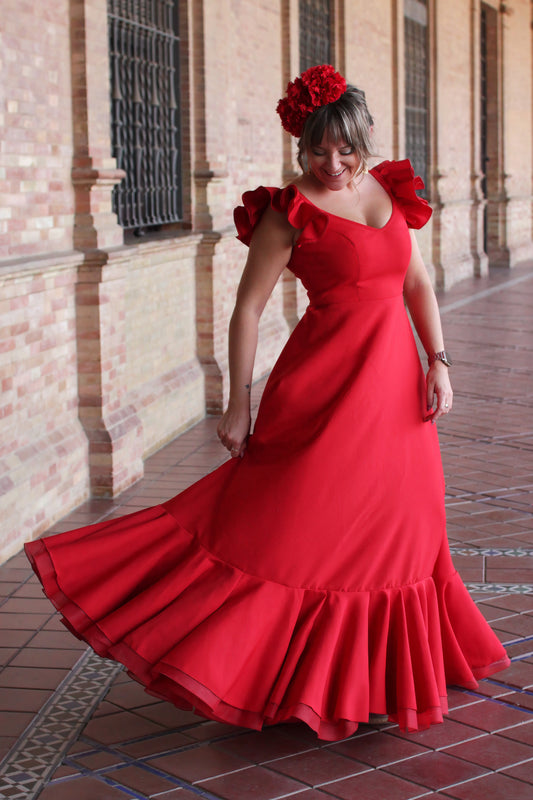 Deslumbra en la romería con el Look Flamenco completo. La Bata Flamenca Roja Girasol, combinada con el Ramillete Rojo Pasión y los Pendientes Dorados Carmona, es el conjunto perfecto para un look lleno de luz y alegría.