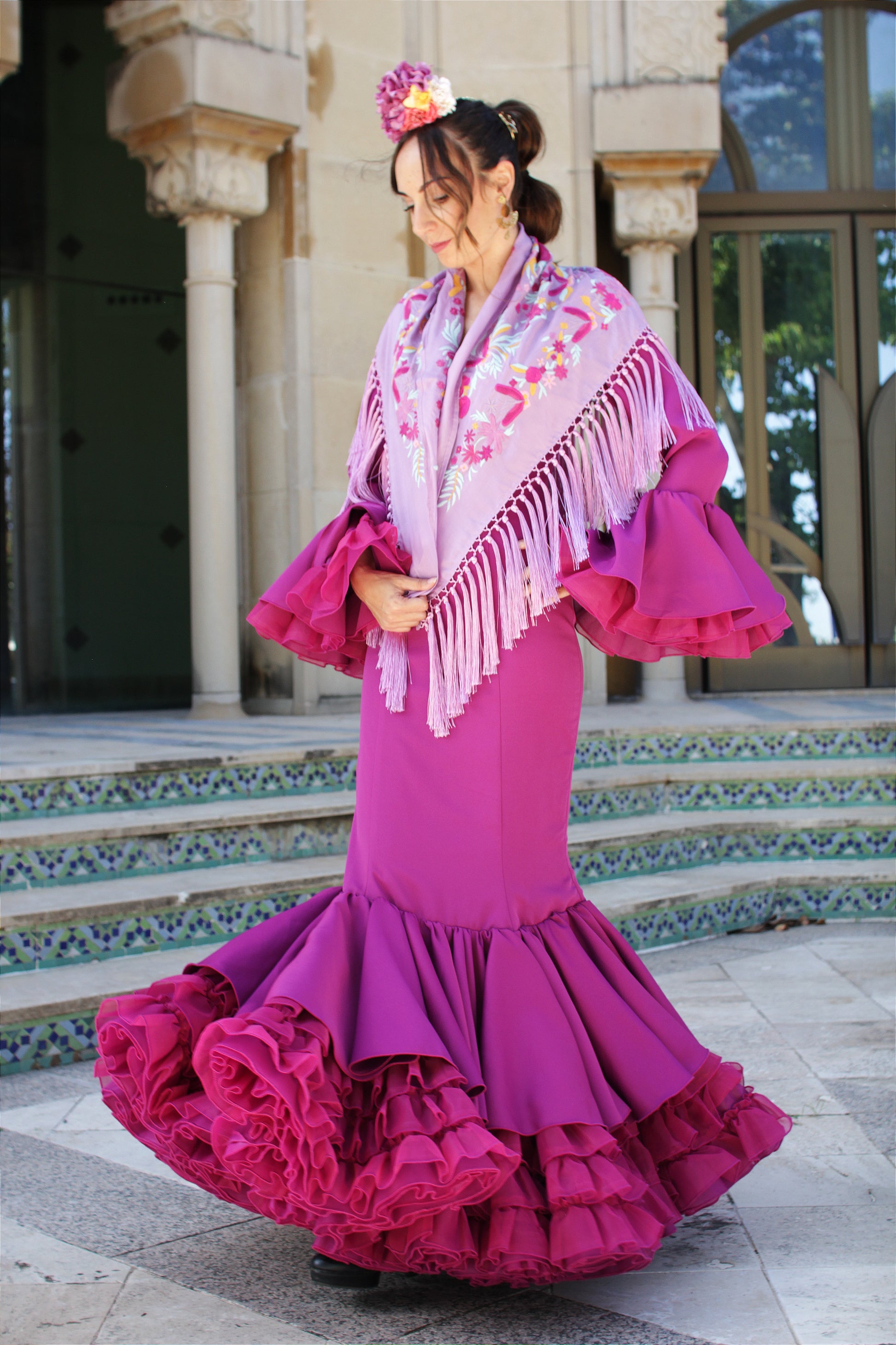 El manton de flamenca lila Elena, con flores en buganvilla y amarillo, es una pieza artesanal de seda. Hecho en Cantillana, perfecto para destacar en la feria con estilo y tradición.